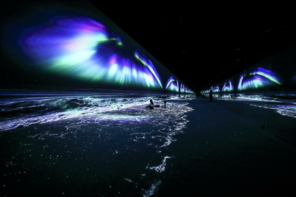 Visitors enjoying a digital representation of the Northern Lights above simulated ocean waves