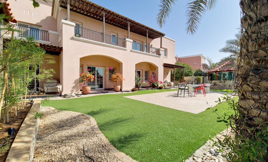 Luxurious villa in Arabian Ranches with a dog playing in the green backyard.