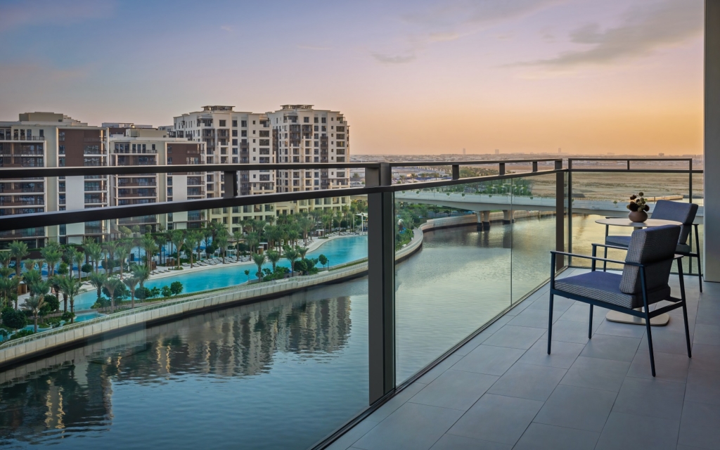 Luxurious Dubai apartment balcony overlooking a private pool at sunset.